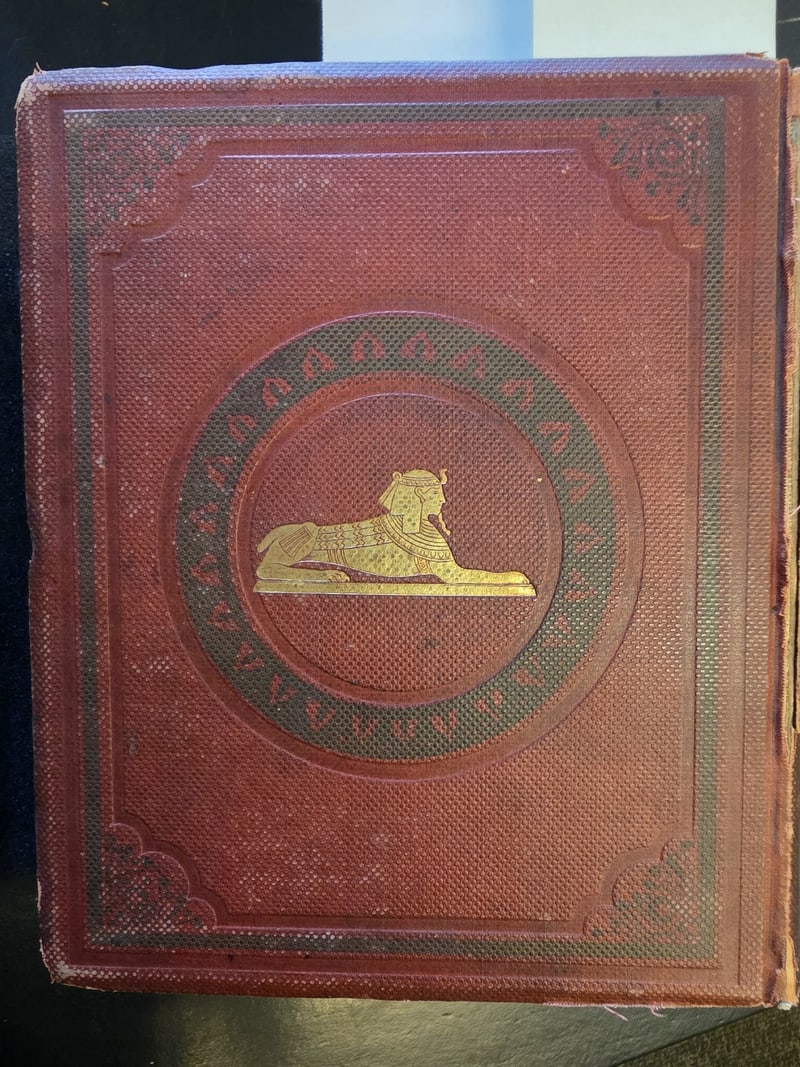 Original red cloth front cover with gilt sphinx and green-stamped band, borders, and corner ornaments
