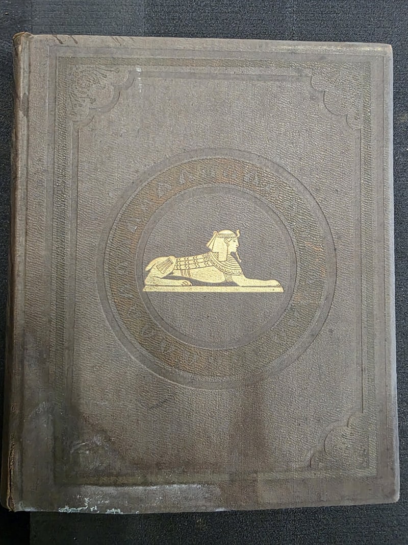 S082: Original brown cloth front board with gilt sphinx and blind-stamped ornament